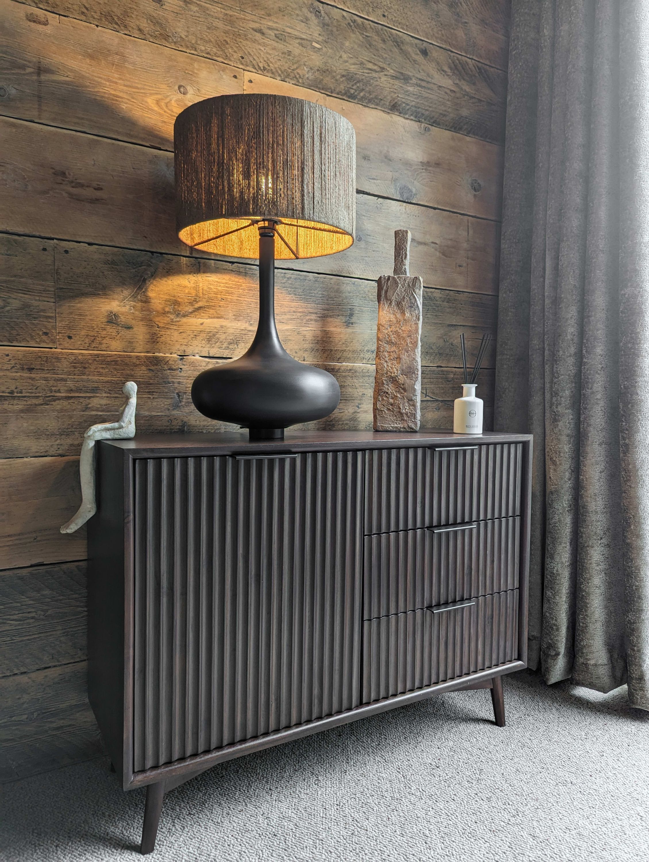 A dark wooden cabinet with a black lamp and a decorative vase.