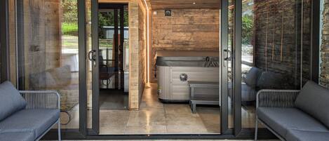 Um interior moderno com uma porta de vidro que dá para um pátio, uma sauna e dois sofás cinzentos.