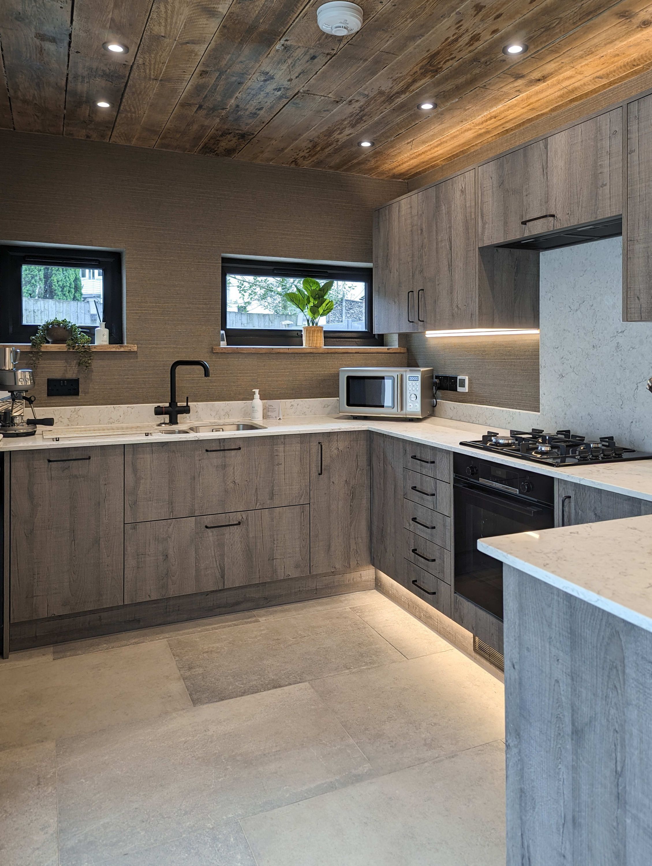 Eine moderne Küche mit Holzschränken, einer eingebauten Mikrowelle und einem Gasherd.