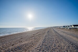 A pebbled beach with a row of seaside cottages.