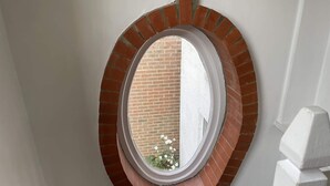 Ein rundes Fenster mit Ziegelbogen, eingelassen in eine weiße Wand.