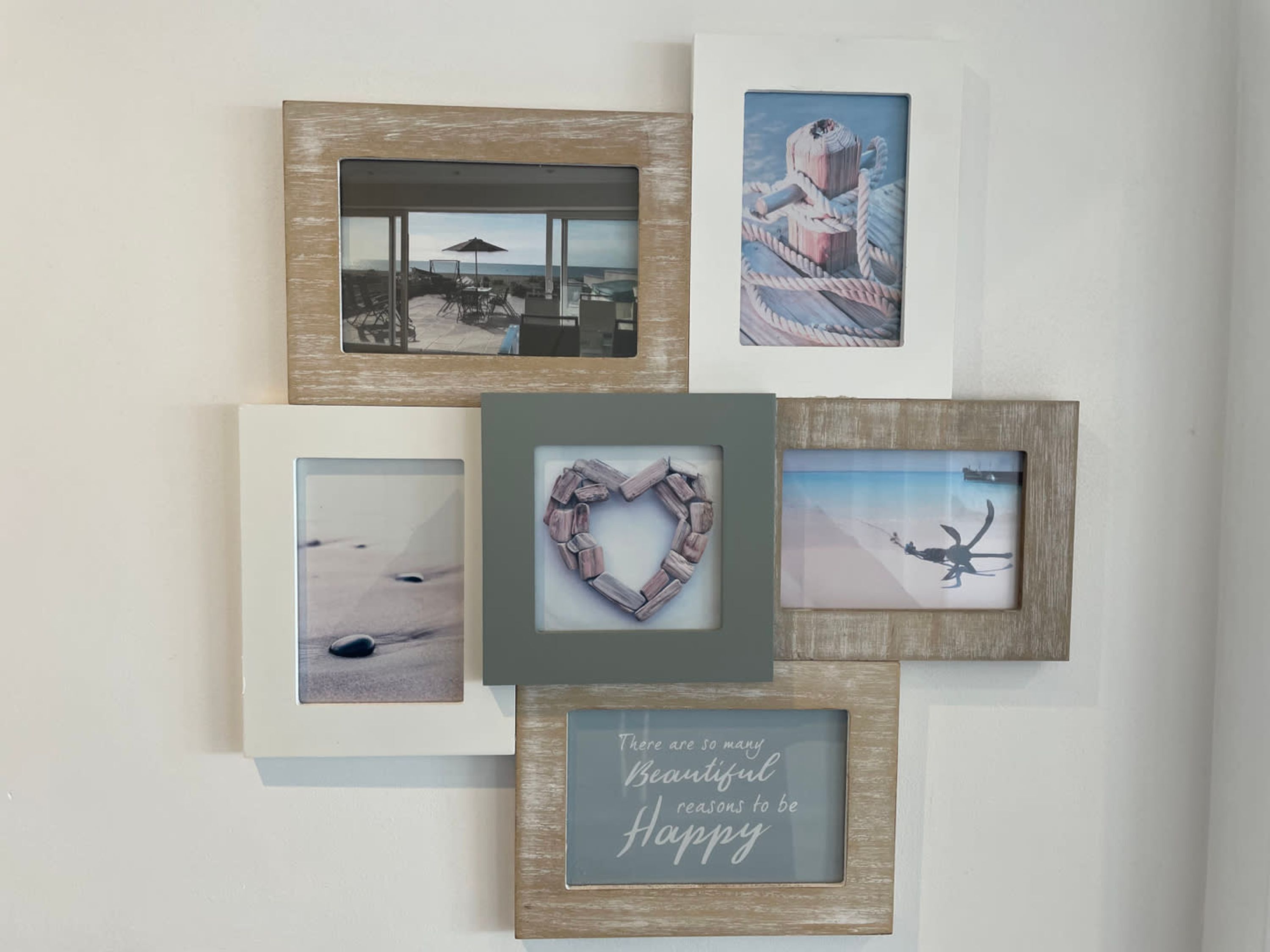 A wall with five framed pictures, including a heart-shaped frame and a quote about happiness.