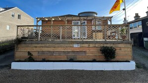 A wooden building with a fenced porch, a flag, and a sign indicating a private car park. - The Crabshack Cottage Normans Bay Pevensey (Pevensey)