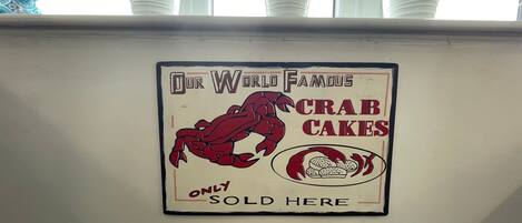 A wall sign advertising 'Our World Famous Crab Cakes' with a crab illustration and text stating 'Only Sold Here'.