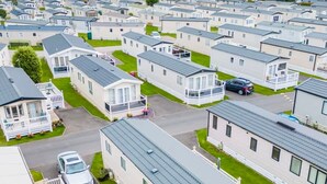 A row of mobile homes with individual driveways and small front yards, arranged in a linear fashion along a beachfront. - Your Ultimate Holiday Rental at Pevensey Bay (Pevensey)