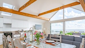 A spacious kitchen with white cabinets, a large island, and a view of the sea.