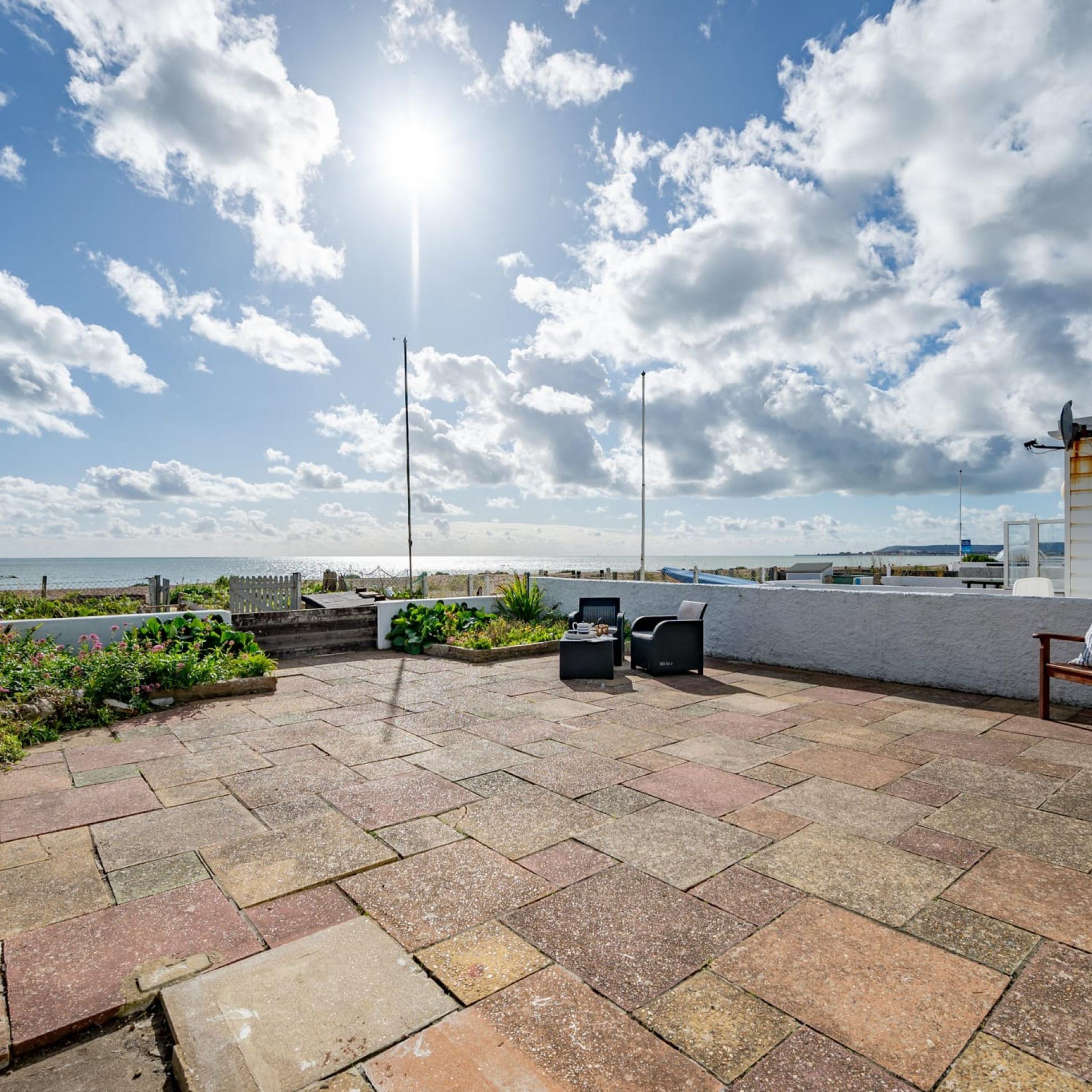 Un patio con baldosas de piedra, muebles de exterior y vista al mar.