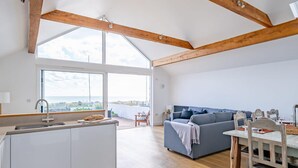 A spacious kitchen with a large island, wooden beams, and a view of the sea.
