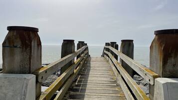 A wooden pier with concrete posts leading to the sea.
