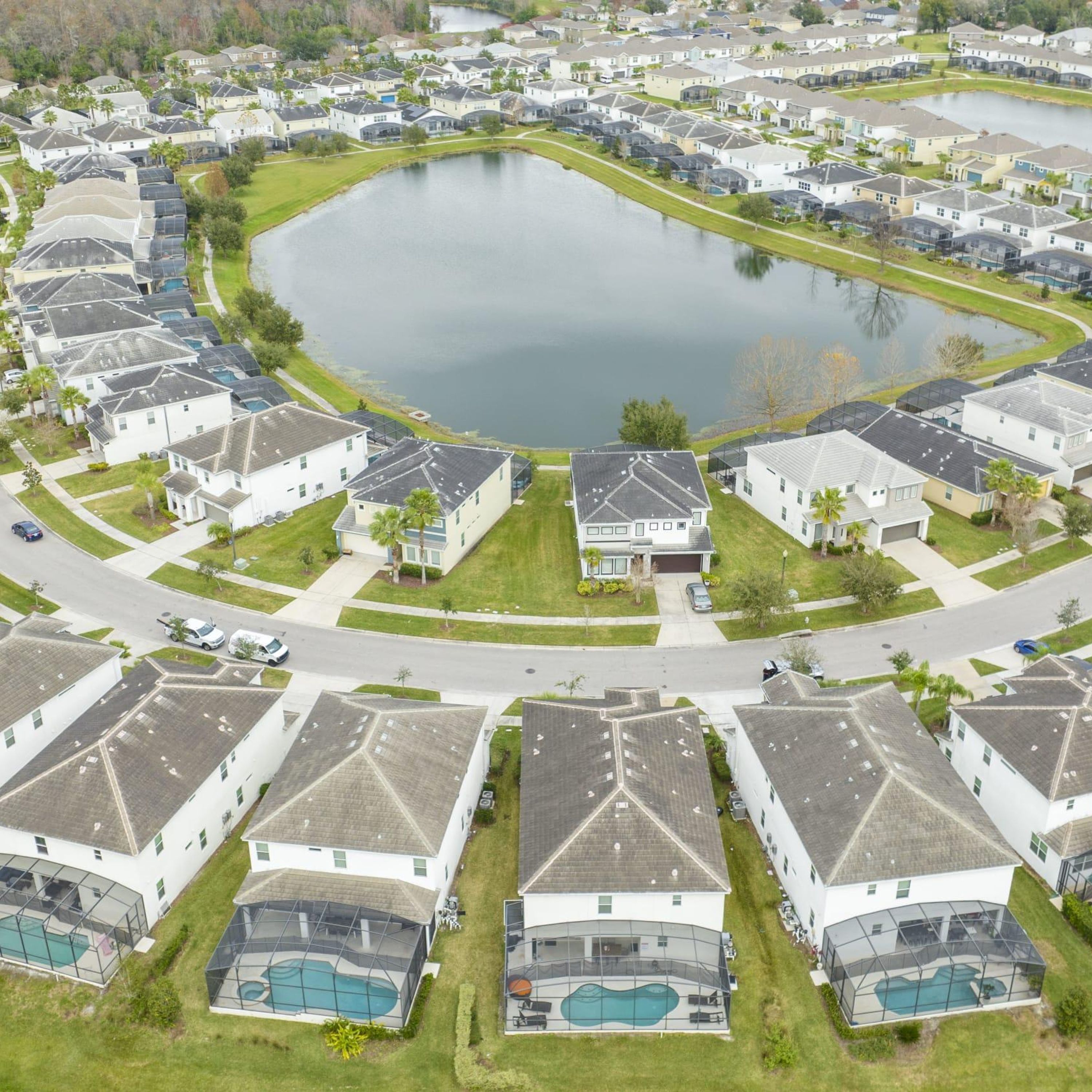 A residential area with houses, a central pond, and a swimming pool.