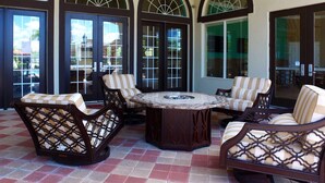 A covered patio area with a round table and four cushioned chairs, large arched windows, and a tiled floor. - Wonderful 12b11 5bath Bella Vida Resort (Kissimmee)