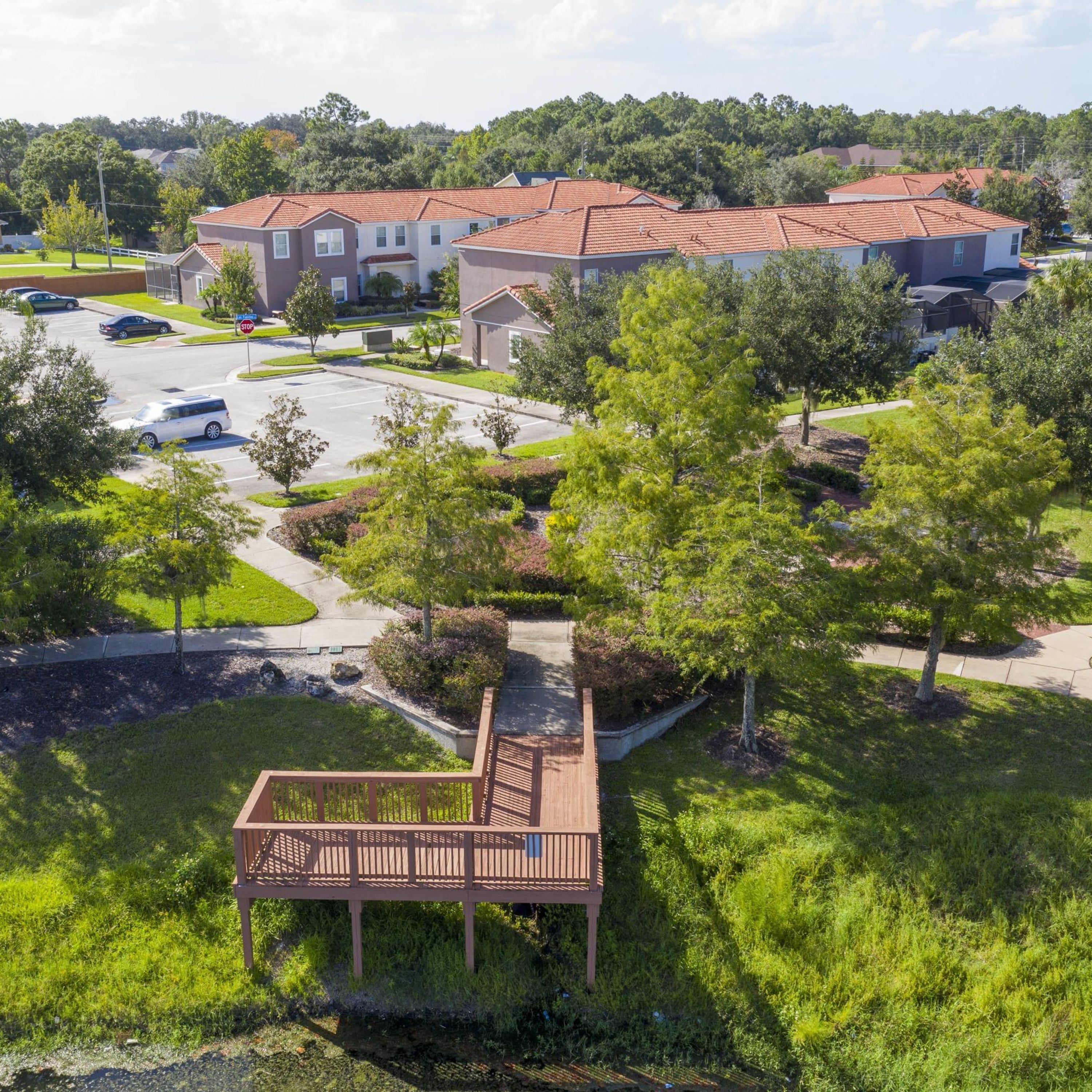 A residential area with a parking lot, a covered deck, and houses with red-tiled roofs.