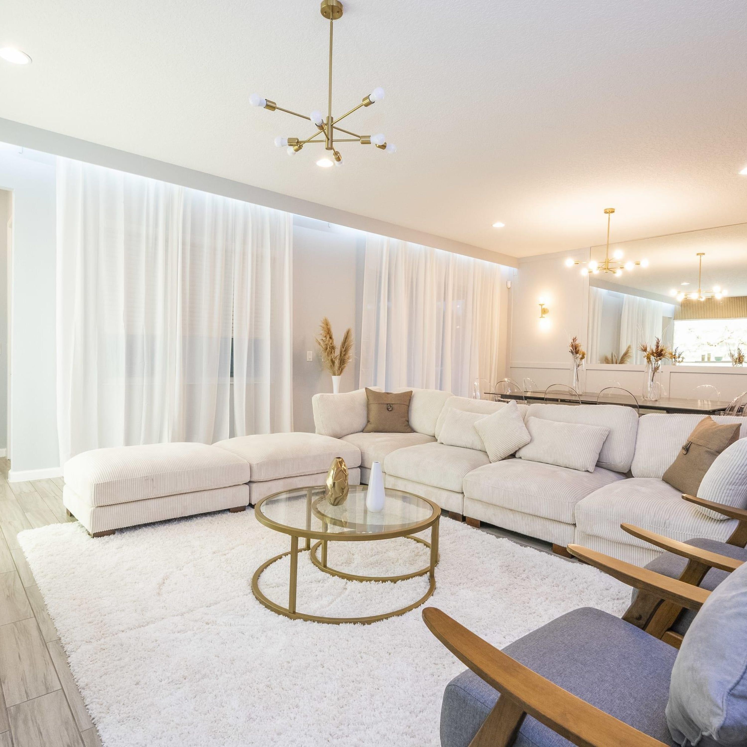 A modern living room with a sectional sofa, a glass coffee table, and a chandelier.