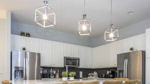 A modern kitchen with white cabinets, stainless steel appliances, and a central island with bar stools. - Wonderful 12b11 5bath Bella Vida Resort (Kissimmee)