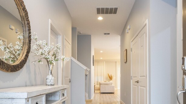 A hallway with a wooden floor, white walls, and a mirror with a branch decoration. - Wonderful 12b11 5bath Bella Vida Resort (Kissimmee)