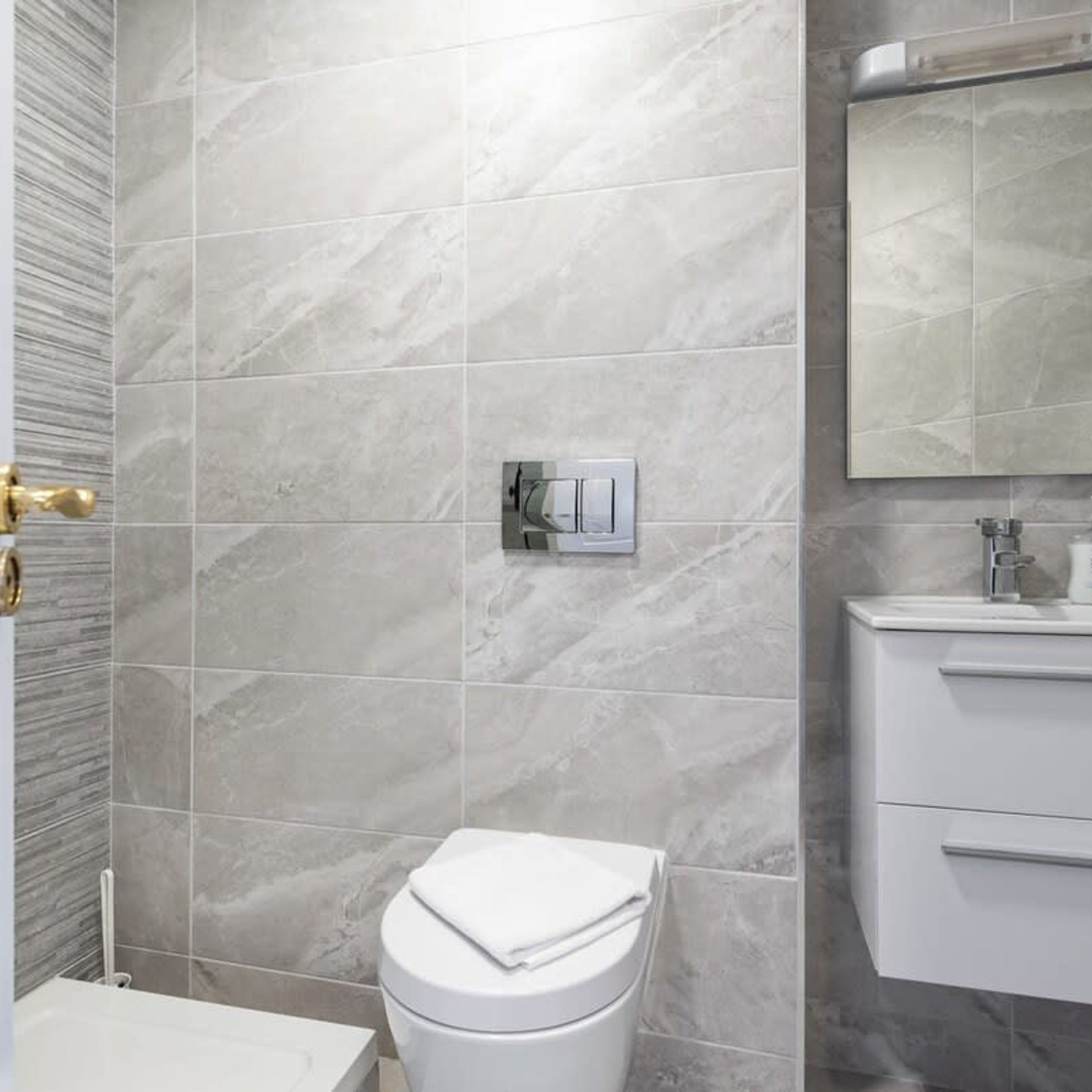 A modern bathroom with a toilet, sink, and mirror.
