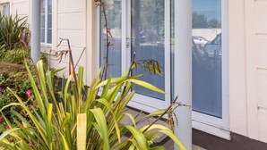 A building with a covered entrance, large glass doors, and a balcony with plants. - Ferncourt Stepaside (Dublin)