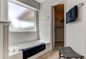 A bathroom with a bathtub, a window, a towel rack, and a bench. - Spacious 3BR Retreat Close to Downtown & Outlets (San Marcos)