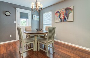 A dining room with a round table, four chairs, a chandelier, and a painting on the wall. - Spacious 3BR Retreat Close to Downtown & Outlets (San Marcos)