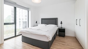 Una camera da letto moderna con un letto grande, un comodino e una finestra vista edifici.