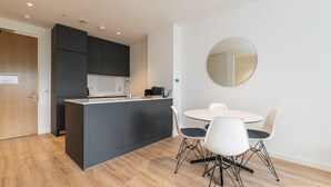 Una cucina moderna con isola centrale, tavolo da pranzo bianco e sedie.