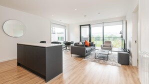 Een modern appartement met een kookeiland, een bank, een eethoek en grote ramen.