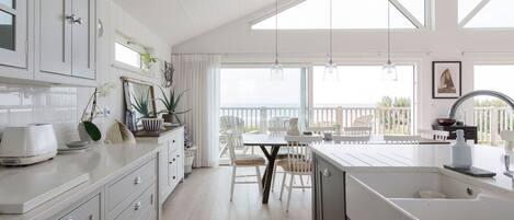 A bright kitchen with white cabinets, a large island with a sink, and a dining area with a table and chairs.