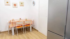 Une cuisine avec une table mise pour quatre personnes, un réfrigérateur et trois tableaux encadrés accrochés au mur.