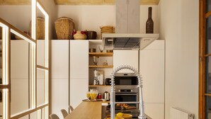 Una cocina moderna con una mesa de comedor de madera, electrodomésticos integrados y un amplio ventanal que proporciona luz natural.