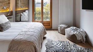 Un dormitorio con una cama grande, una ventana con vistas, un radiador y un televisor montado en la pared.