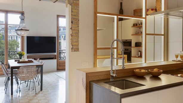 Una cocina moderna con una isla grande, horno empotrado y comedor con mesa y sillas.