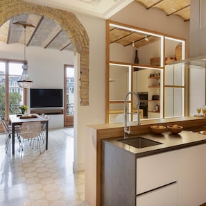 Una cucina moderna con una grande isola, forno a incasso e zona pranzo con tavolo e sedie.