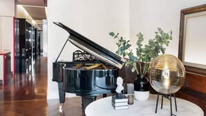 Un piano à queue dans une pièce spacieuse, avec une table en marbre, des livres et des objets décoratifs.