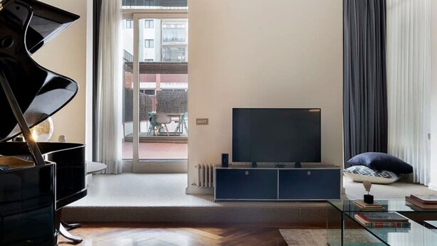 Un salon avec un piano, un téléviseur à écran plat et une table basse en verre.