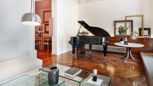 Un salon spacieux agrémenté d’un magnifique piano à queue, d’une table basse en verre et d’un lustre moderne.