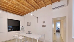 Une cuisine moderne avec des meubles blancs, un plan de travail en marbre et un plafond en bois.