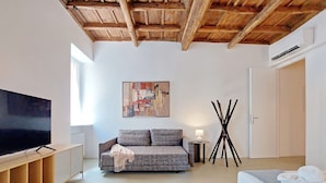 Un salon moderne avec un canapé, un téléviseur, un tableau et un lit.