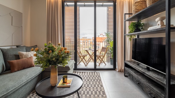 Un soggiorno moderno con un divano, un tavolino da caffè e una TV su un mobile in legno.