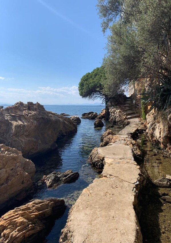 Un sentier côtier qui traverse un terrain rocheux et offre une vue dégagée sur la mer.