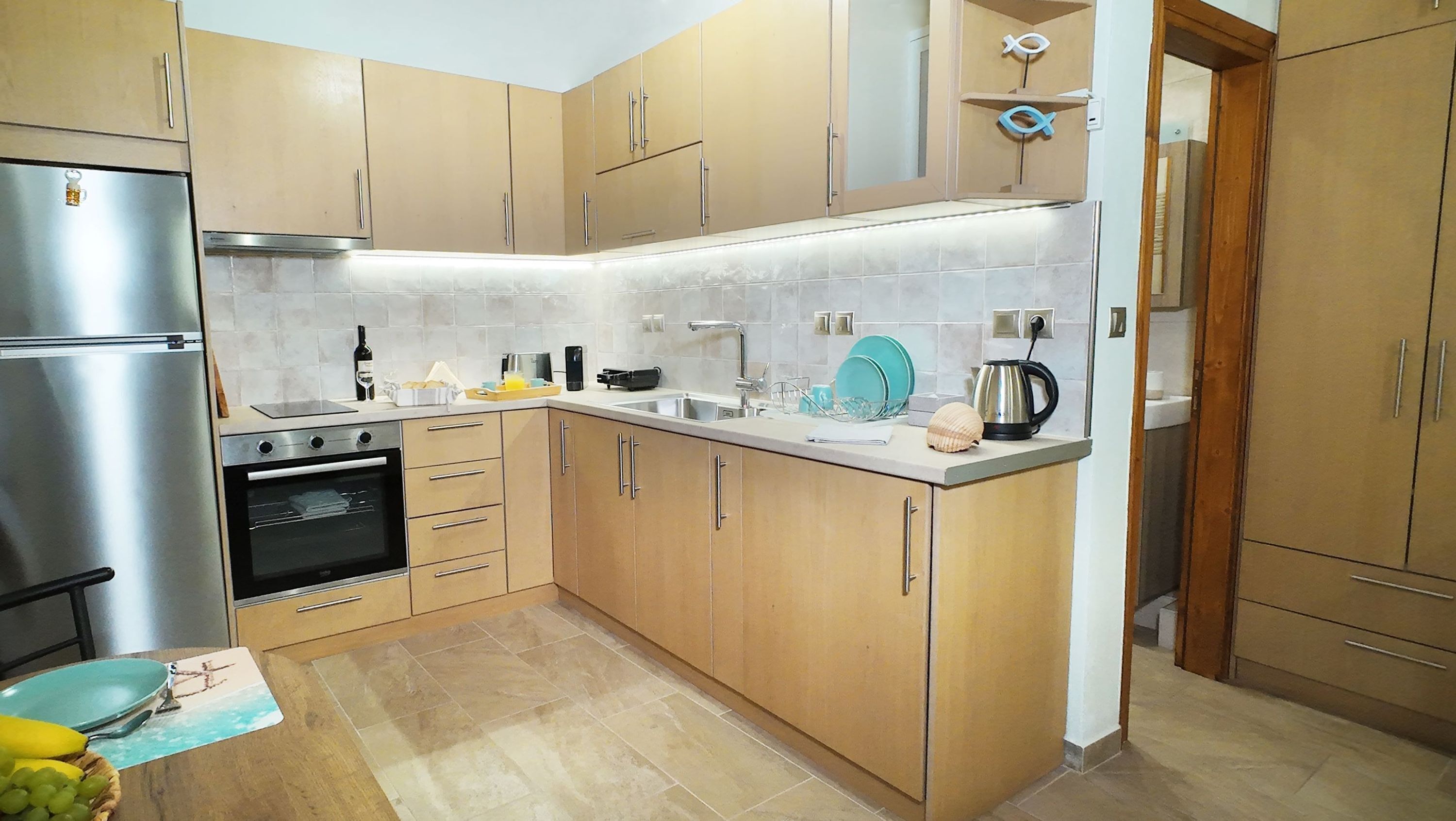 A modern kitchen with stainless steel appliances, wooden cabinets, and a tiled backsplash.