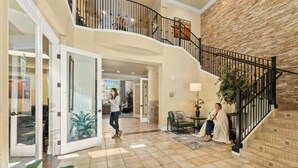 A spacious interior with a central open area, a staircase with a black railing, and a stone wall. - Relaxing 2-br Apt With Pool Hot Tub Gym and Basketball Court Access (Reno)