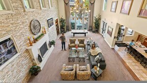 A spacious living room with a fireplace, stone wall, and a large chandelier. - Relaxing 2-br Apt With Pool Hot Tub Gym and Basketball Court Access (Reno)
