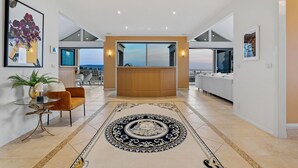A spacious living area with a large window, a central wooden coffee table, and a patterned rug. - Sunset View Luxury 4 Bedrooms With Sauna (Mount Martha)