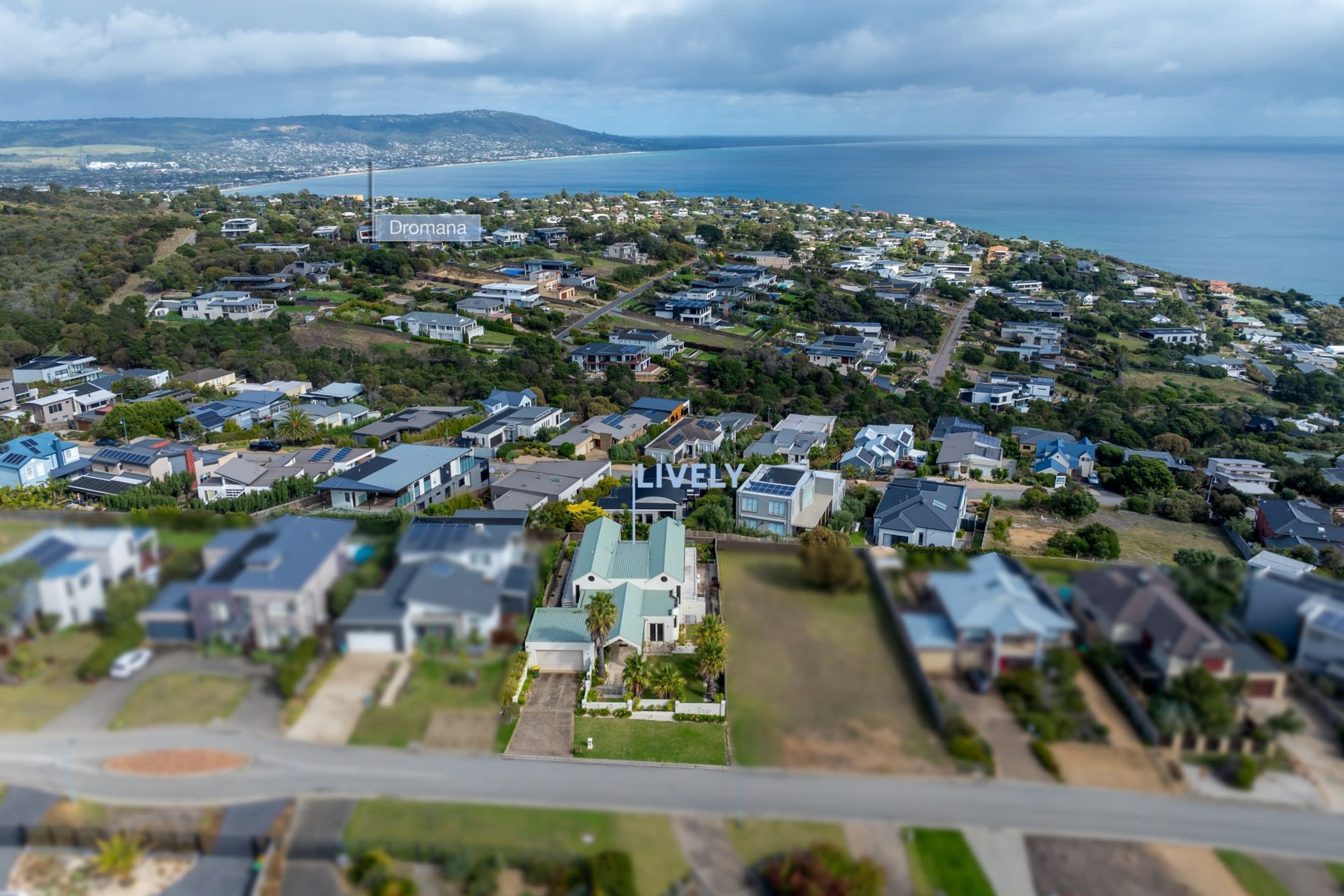 Un quartier résidentiel avec des maisons, un bâtiment imposant portant l’inscription « Dromana », et une vue sur la mer.