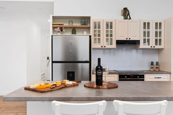 A modern kitchen with a stainless steel refrigerator, wooden countertop, and white cabinets. - Skyline Views Yarra Valley s Elevated Escape (Yarra Glen)