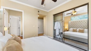 A hotel room with a large bed, a ceiling fan, a walk-in closet, and a sliding glass door to the bathroom.