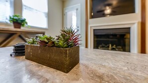 A kitchen with a marble countertop, a potted plant, and a fireplace in the background. - Marketing in Reno With 2 Bedrooms and 2 Bathrooms (Reno)