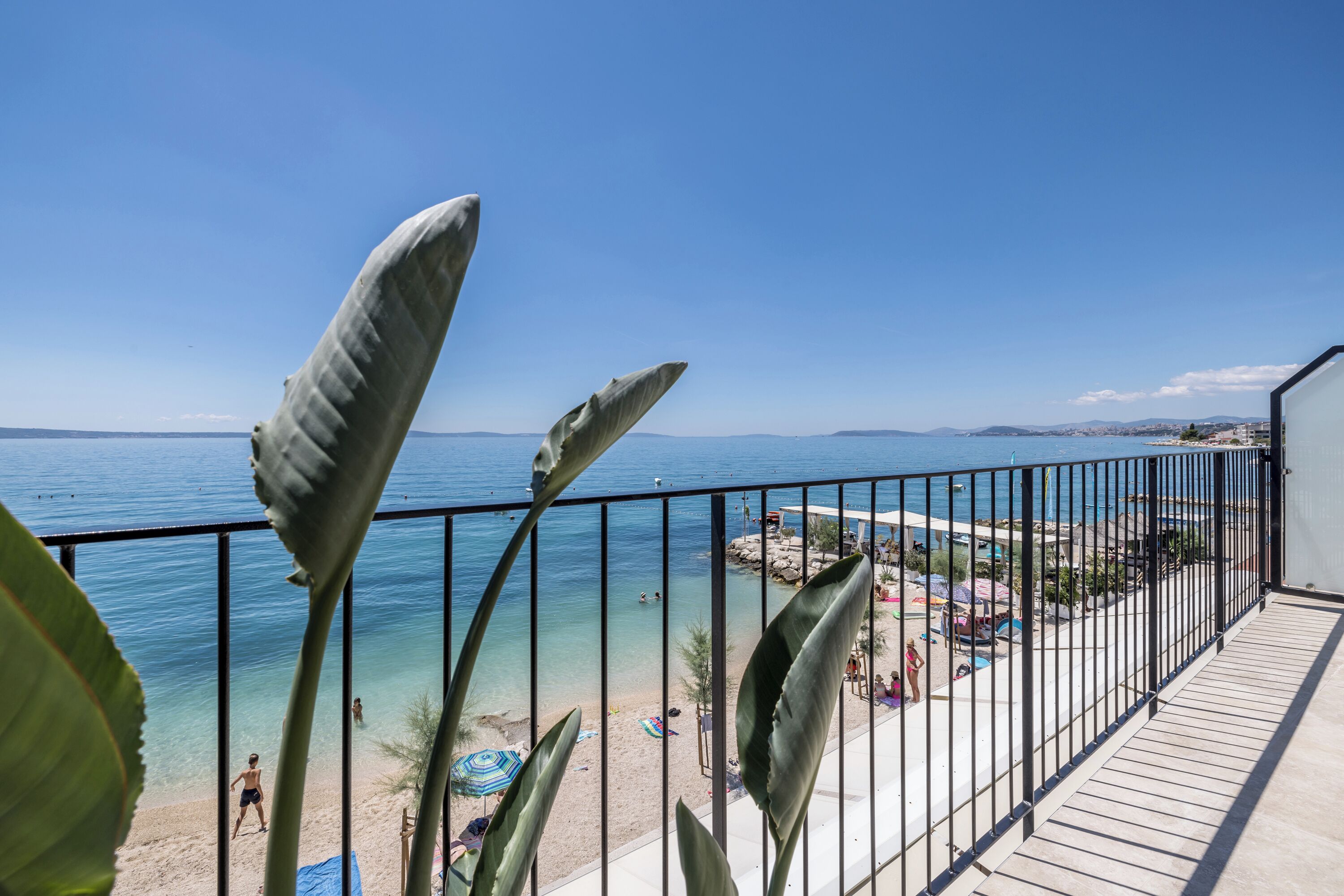 A balcony with a view of a beach and the sea.