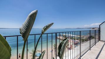 A balcony with a view of a beach and the sea.