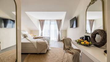 A modern bedroom with a large bed, a round woven rug, a wicker chair, a mirror, and a fruit basket on the dresser.